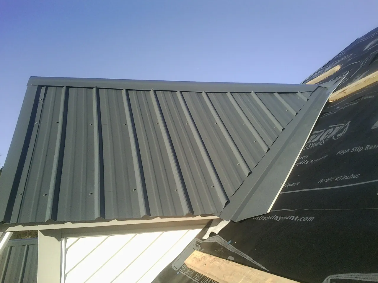 Gray metal roof panels going on over a garage gable in Sulligent