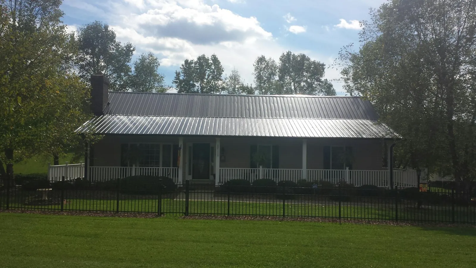 Gray metal roof on a brick ranch with a full width front porch — Gutter Guard Installation work by our crew in Sulligent