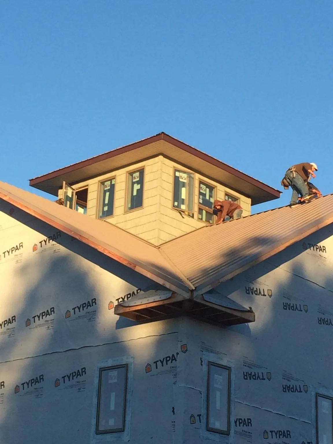 Roofers working around a rooftop cupola on a new metal roof at sunset — Roof Waterproofing in Sulligent by Roofing Brothers